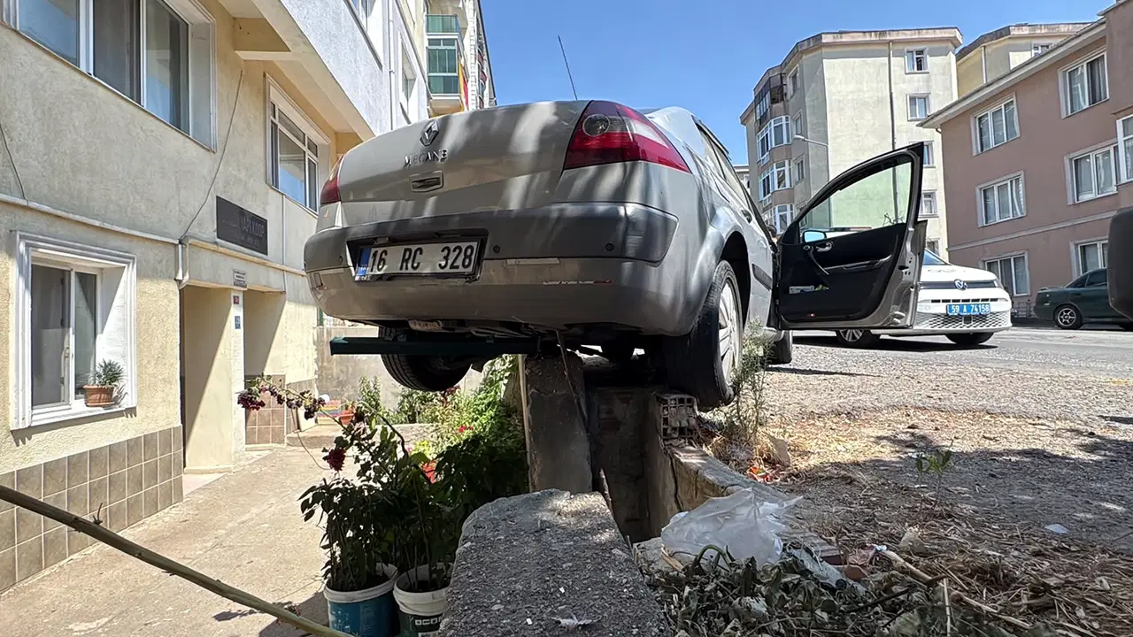 El freni çekilmeyen otomobil, hareket edip istinat duvarında asılı kaldı